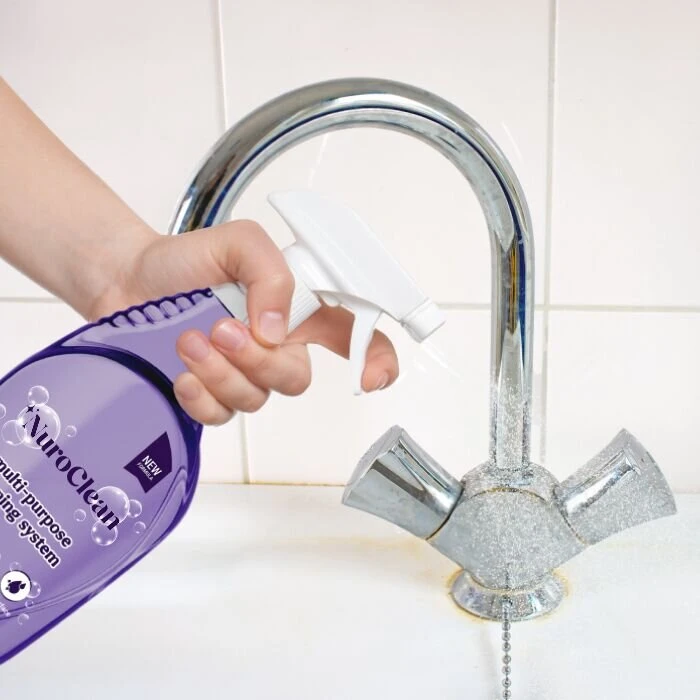Hand holding a NuroClean bottle with finger on the trigger beside a chrome faucet.