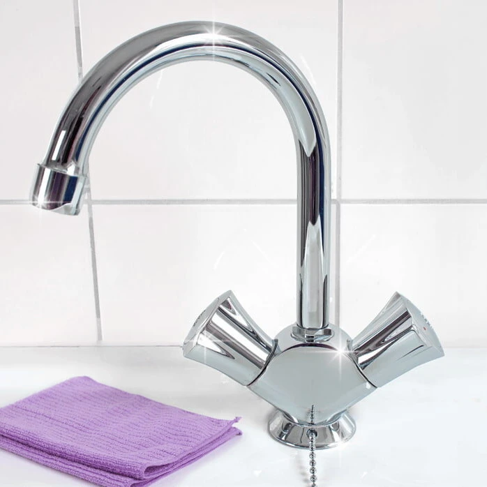 Polished chrome faucet beside a folded purple microfiber cloth on a white sink.