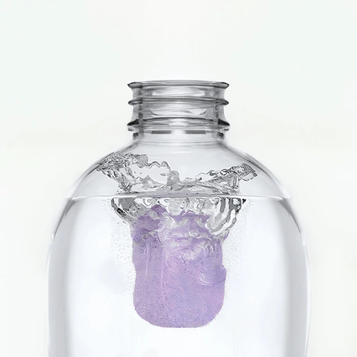Purple cleaning tablet fizzing as it dissolves in clear water.